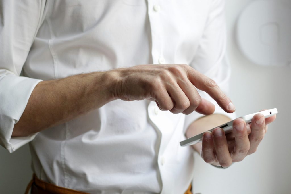 Person mit weißem Android-Smartphone im weißen Hemd
